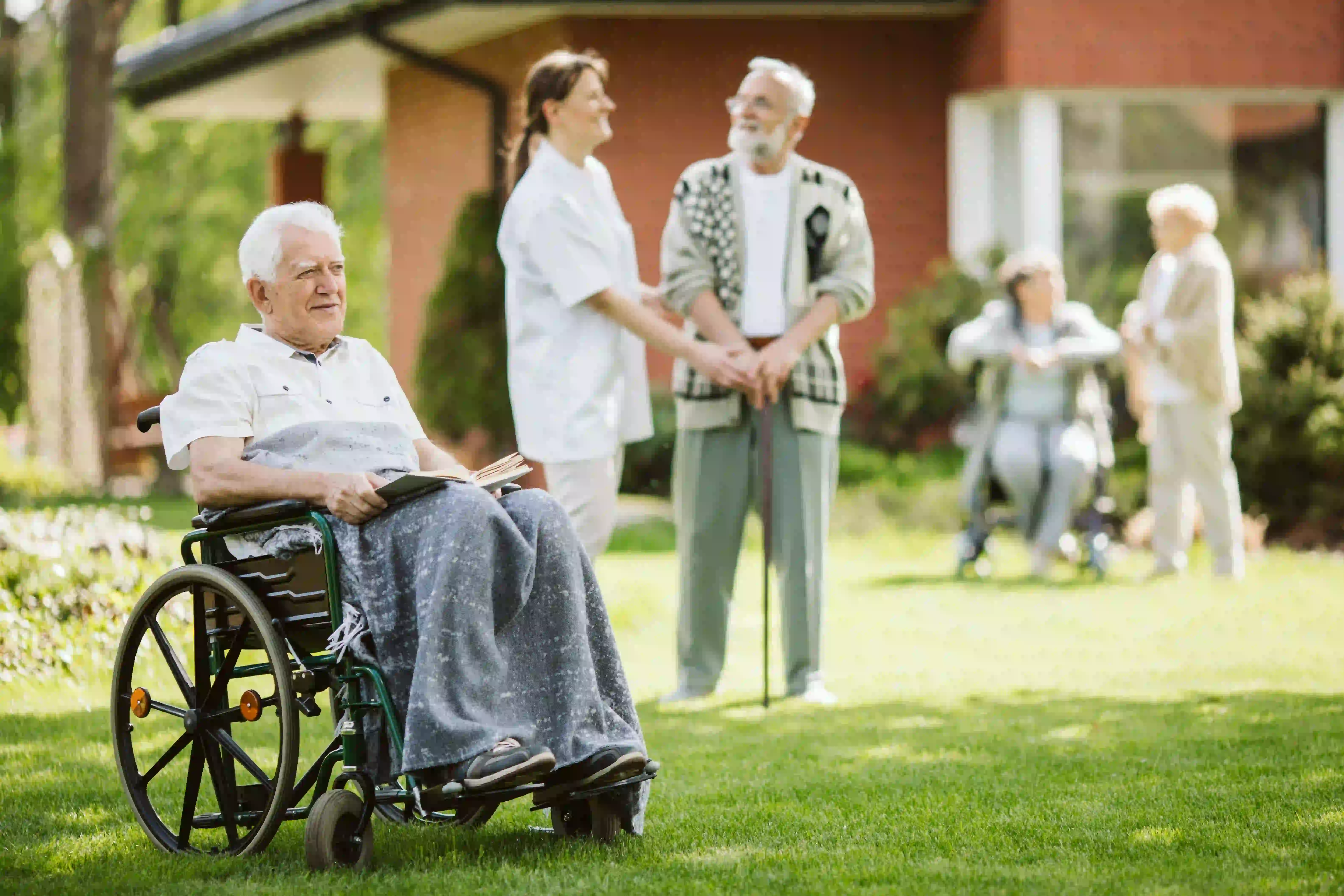 A caregiver sitting outdoors with a group of seniors in a garden
