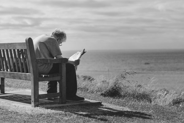 Elderly loved one sitting on a bench overlooking the ocean - healthy aging