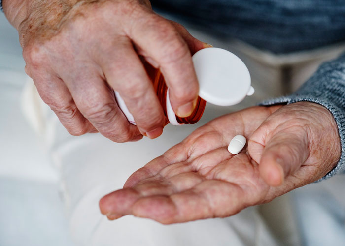 Senior hand holding a single pill - vitamins for seniors